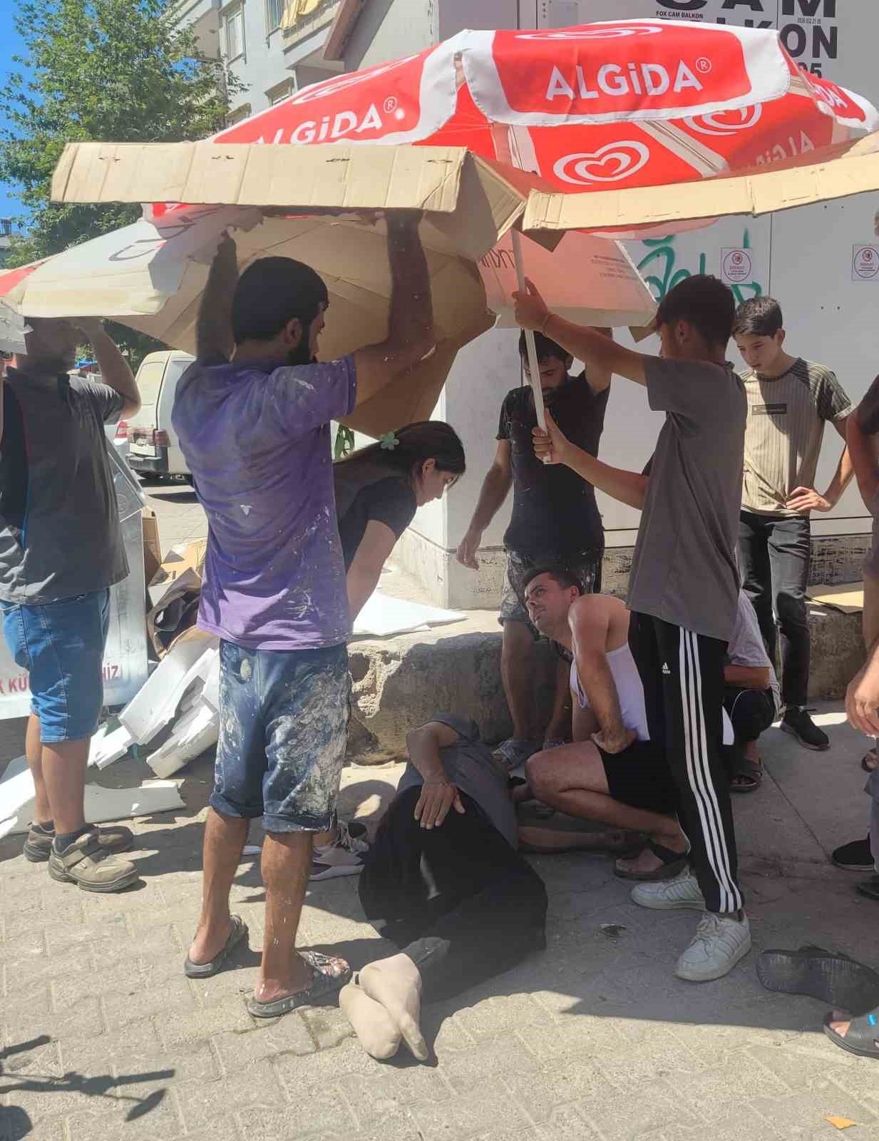 Sağlık ekiplerini beklerken yaralıyı güneşten korumak için seferber oldular