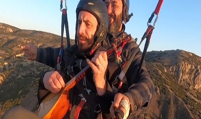 Yamaç paraşütüyle atladı, havada cura çalıp türkü söyledi
