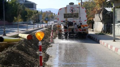 Muhtar, toz çıkmasın diye caddeyi suluyor